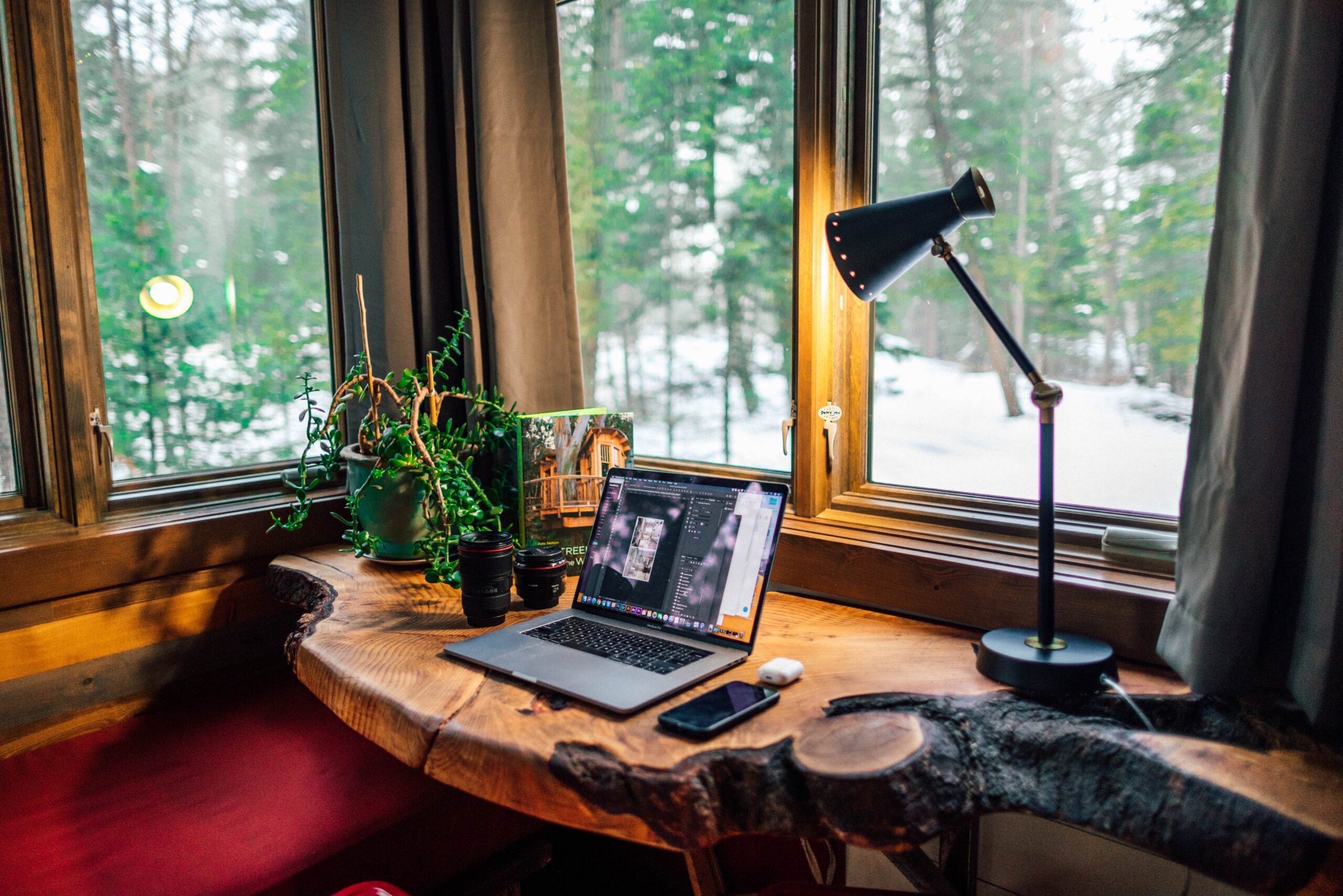 home office setup with laptop and lamp on wooden desk by window or remote workforce